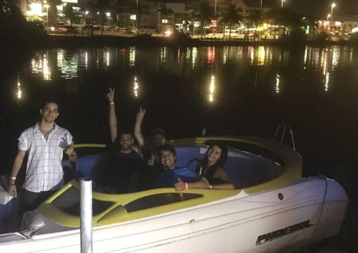 Friends on a boat at night with city lights reflected on the water