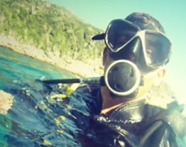 Raphael in a wetsuit with mask and snorkel at the surface