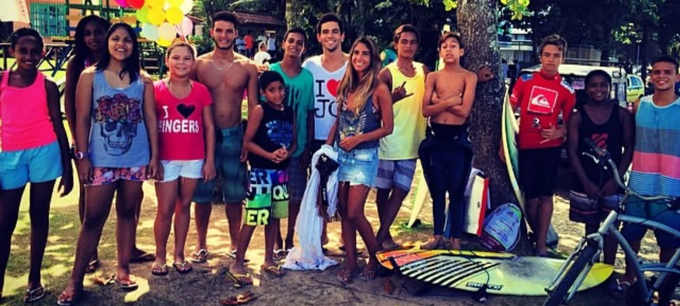 A large group of kids and teens holding surfboards in a park