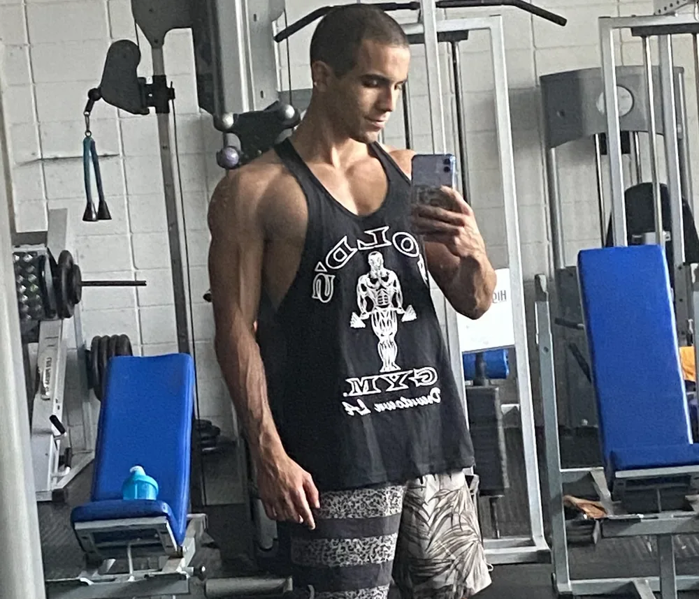 Raphael in the gym, mirror selfie wearing a Gold's Gym tank top