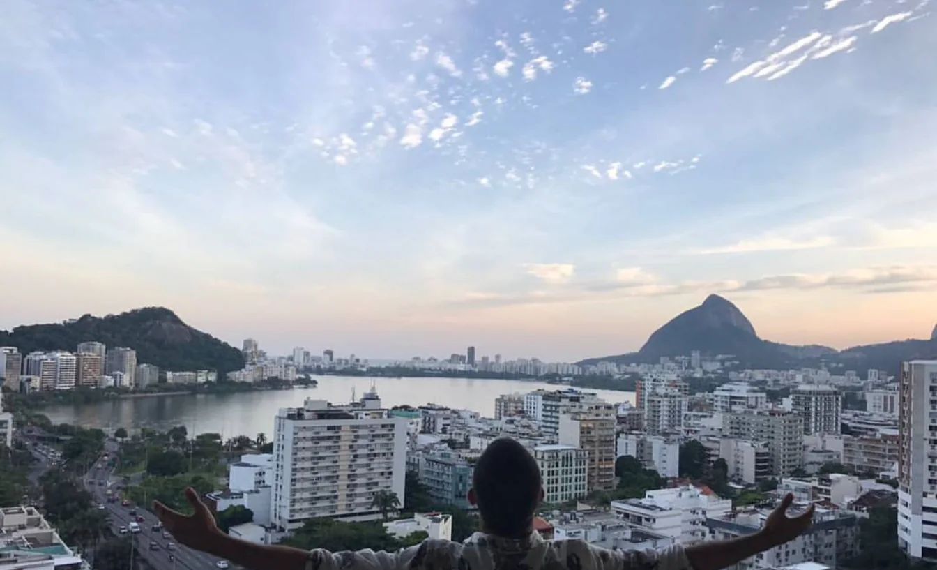 Raphael seen from behind with open arms over a city and lagoon at sunset