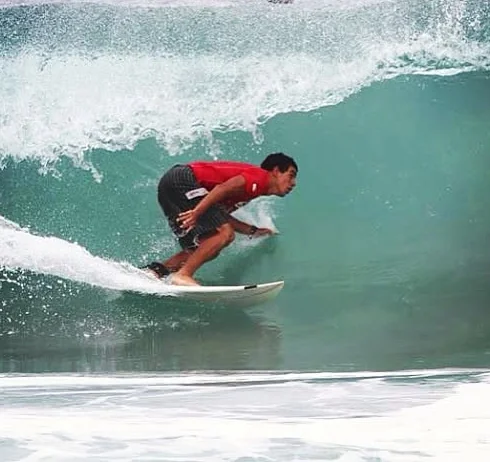 Raphael surfing in a red shirt