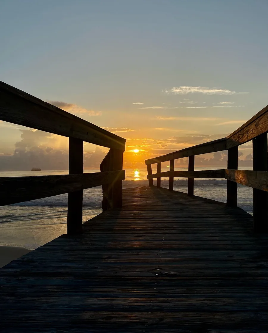 A wooden pier leading to the sea at sunrise