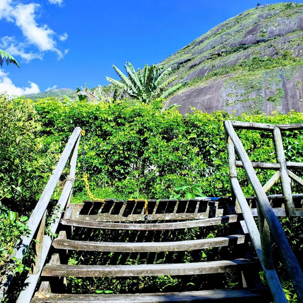 Wooden stairs climbing toward a green mountain under a blue sky