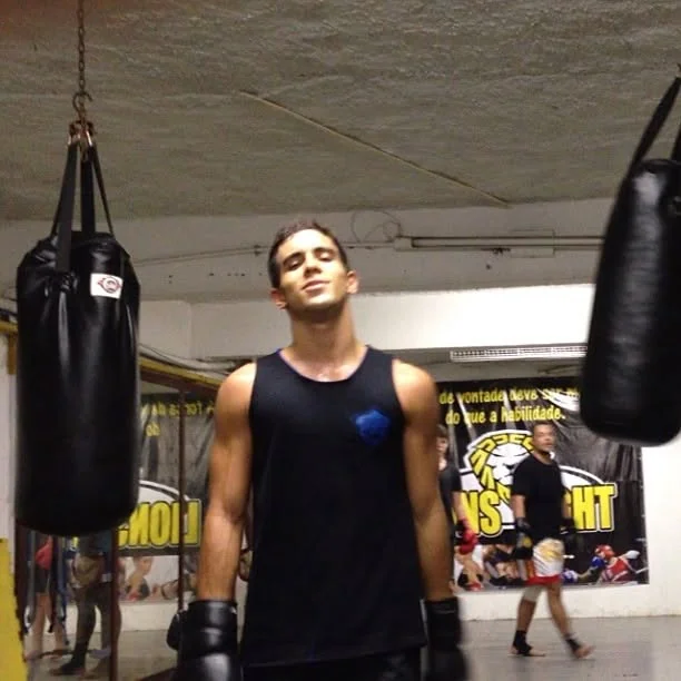 Raphael in boxing gloves at the gym between heavy bags